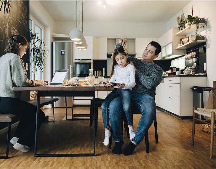 Famille dans une cuisine, un parent aide une enfant à lire