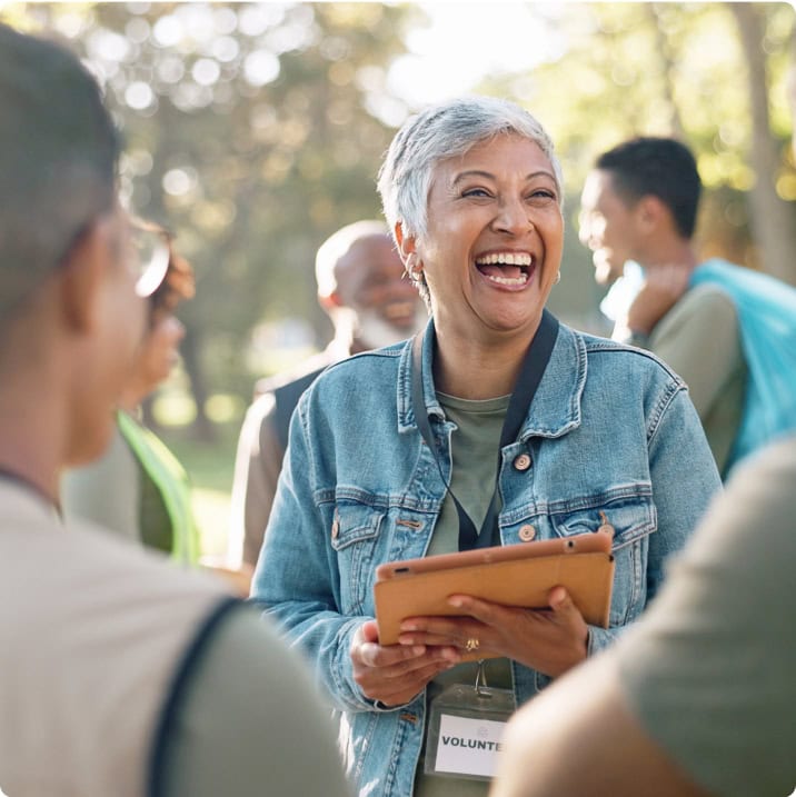 Femme souriante tenant une tablette lors d’une rencontre en plein air