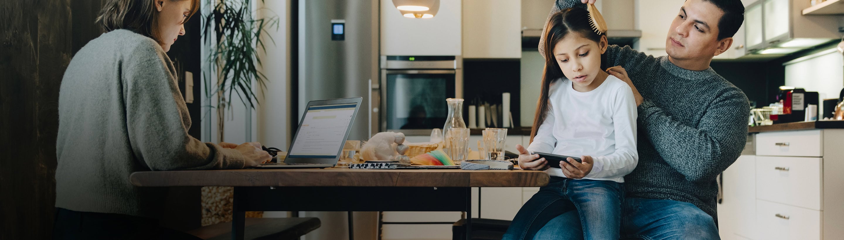 Famille dans une cuisine, un parent aide une enfant à lire
