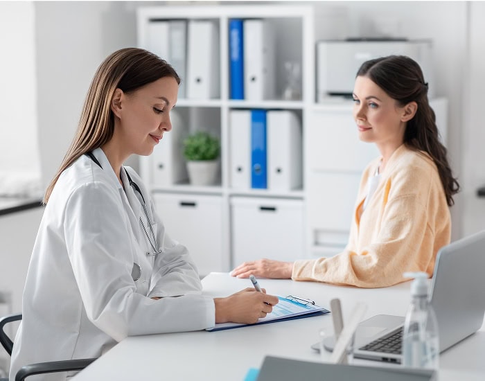 Médecin prenant des notes face à une patiente