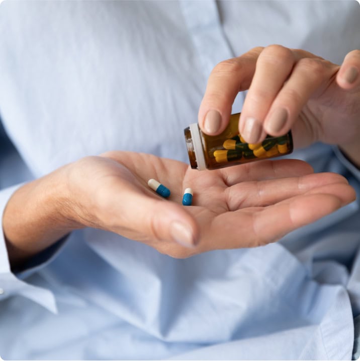Personne versant des gélules dans sa main depuis un flacon